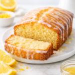 Gâteau au citron moelleux fait maison, nappé de glaçage au citron, avec une tranche coupée montrant l’intérieur fondant.