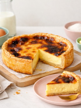 Flan traditionnel sur pâte feuilletée avec une part coupée, présenté sur vaisselle pastel dans une ambiance lumineuse.