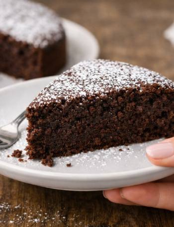 part de moelleux au chocolat fondant classique sur assiette tenue par une main de femme