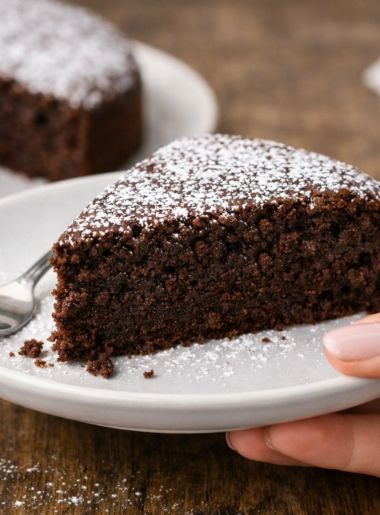 part de moelleux au chocolat fondant classique sur assiette tenue par une main de femme