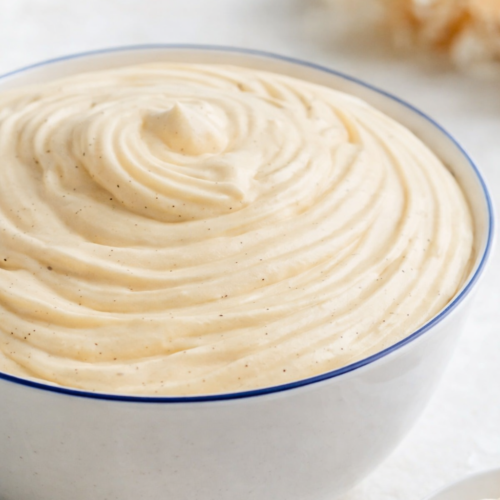 Crème diplomate vanille dans un saladier en céramique blanc à liseret bleu, texture lisse et crémeuse, lumière naturelle douce.