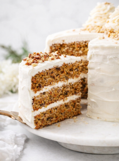 Tranche de carrot cake moelleux aux noix de pécan sur fond lumineux naturel, style éditorial moderne.